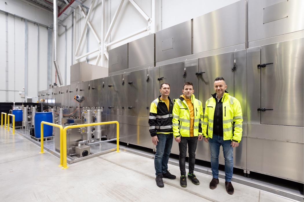 Innerhalb von sechs Monaten hat Craiss die Reinigungsanlage in Sibiu implementiert. (v.l.) Ioan Hundorfean, Leitung Lager und Spedition, Tudor Beju, Gruppenleitung Lagerlogistik, und Horia Matei, Geschäftsführer von Craiss Rumänien, vor der Anlage, die bis zu 800 Behälter pro Stunde reinigen können soll. Foto: Craiss