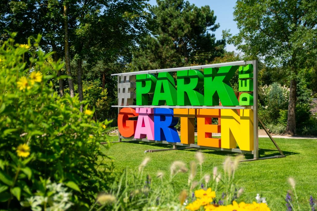 Farbenfrohes Wahrzeichen im Grünen: Der Schriftzug „Park der Gärten“ begrüßt Besucherinnen und Besucher auf dem Gelände der größten Mustergartenanlage Deutschlands in Bad Zwischenahn. | Foto: Gartenkulturzentrum Niedersachsen - Park der Gärten gGmbH