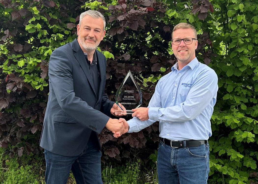 Zum zwanzigjährigen Jubiläum des Craiss-Standorts Warburg überreicht Marco Koltermann (li.), Standortleiter Logistikzentrum Warburg und Kleinenberg bei Craiss, eine Trophäe an Ralf Schulte (re.), Logistik Manager bei Benteler in Warburg. (Foto: Craiss)